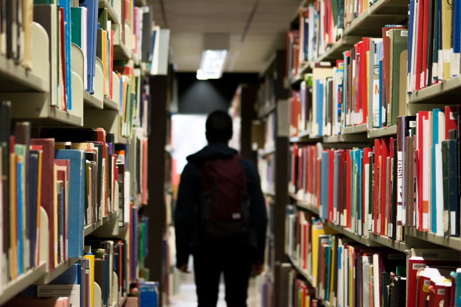 A student walking through library shelves.