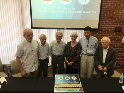 Six figures stand around a cake labeled CEAPS 50th Anniversary