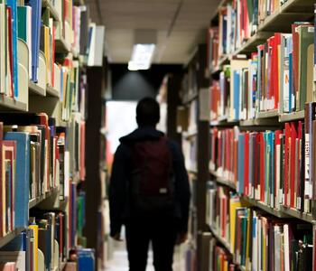 A student walking through library shelves.